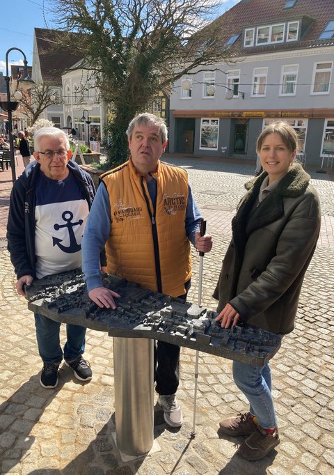 Horst Rieger (Behindertenbauftragter Stadt Schleswig) Carsten Lasarsch (Inklusives Schleswig) und Josephine Schäfer (Stadtplanung Stadt Schleswig) vor dem neuen bronzenen Stadtmodell am Kornmarkt
