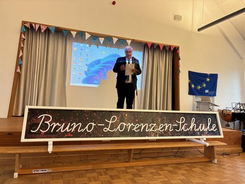 Bürgermeister Dose auf einer Bühne in der Bruno Lorenzen Schule, zur Verleihung des Siegels "Global School". 