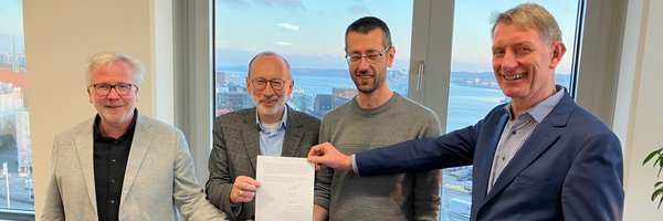 Bernward Völmicke, Stadt Schleswig, Bernd Hannemann, Diakonie Stiftung Schleswig-Holstein, Alexander Opitz, Stadt Schleswig, Kay-Gunnar Rohwer, Diakonie Stiftung Schleswig-Holstein halten einen unterschriebenen  Kaufvertrag in der Hand