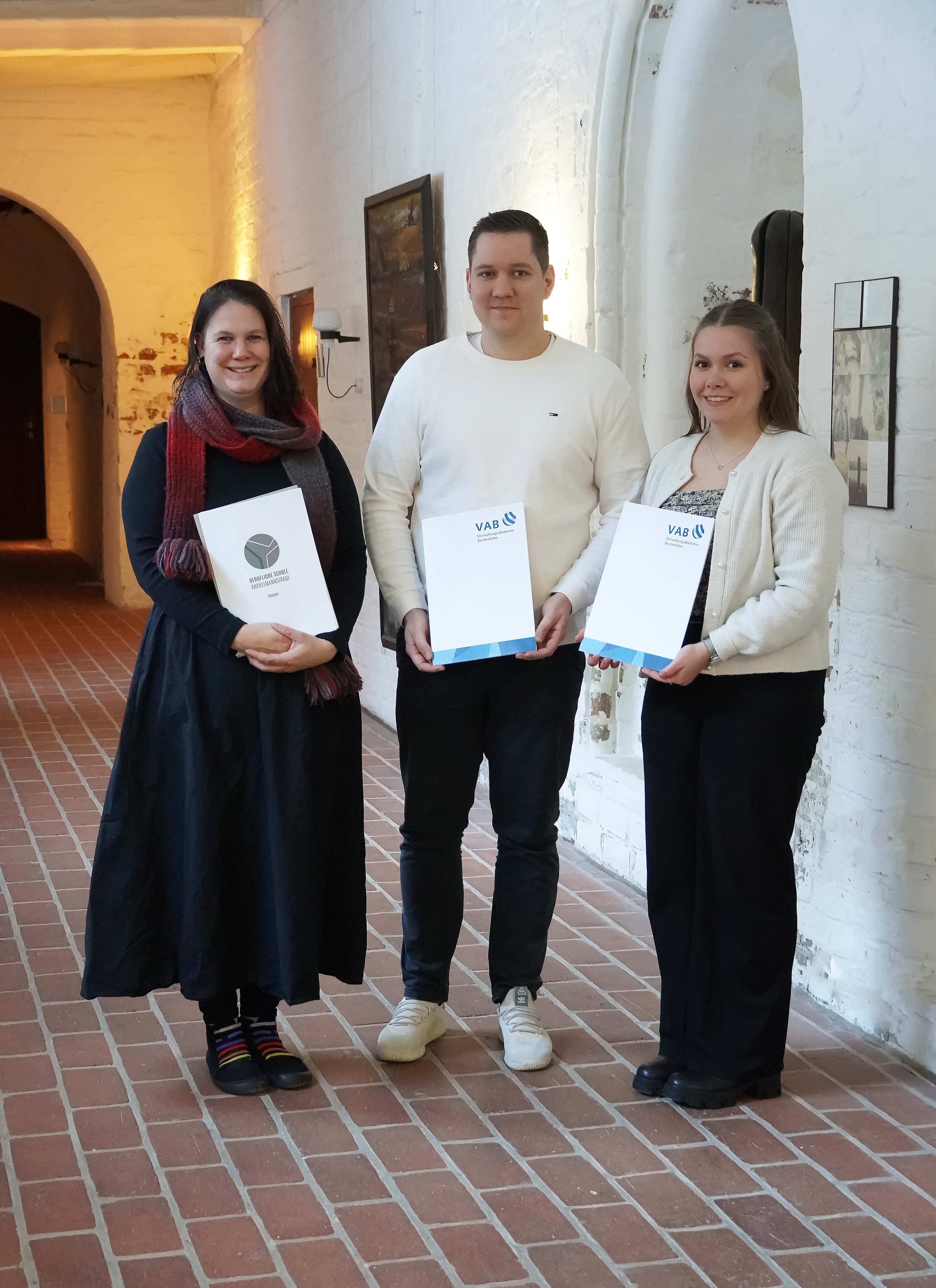 Tahmani Carstensen, Arne Albertsen und Hannah Jürgens mit dem Ausbildungszeugnis im Gang des Grauklosters